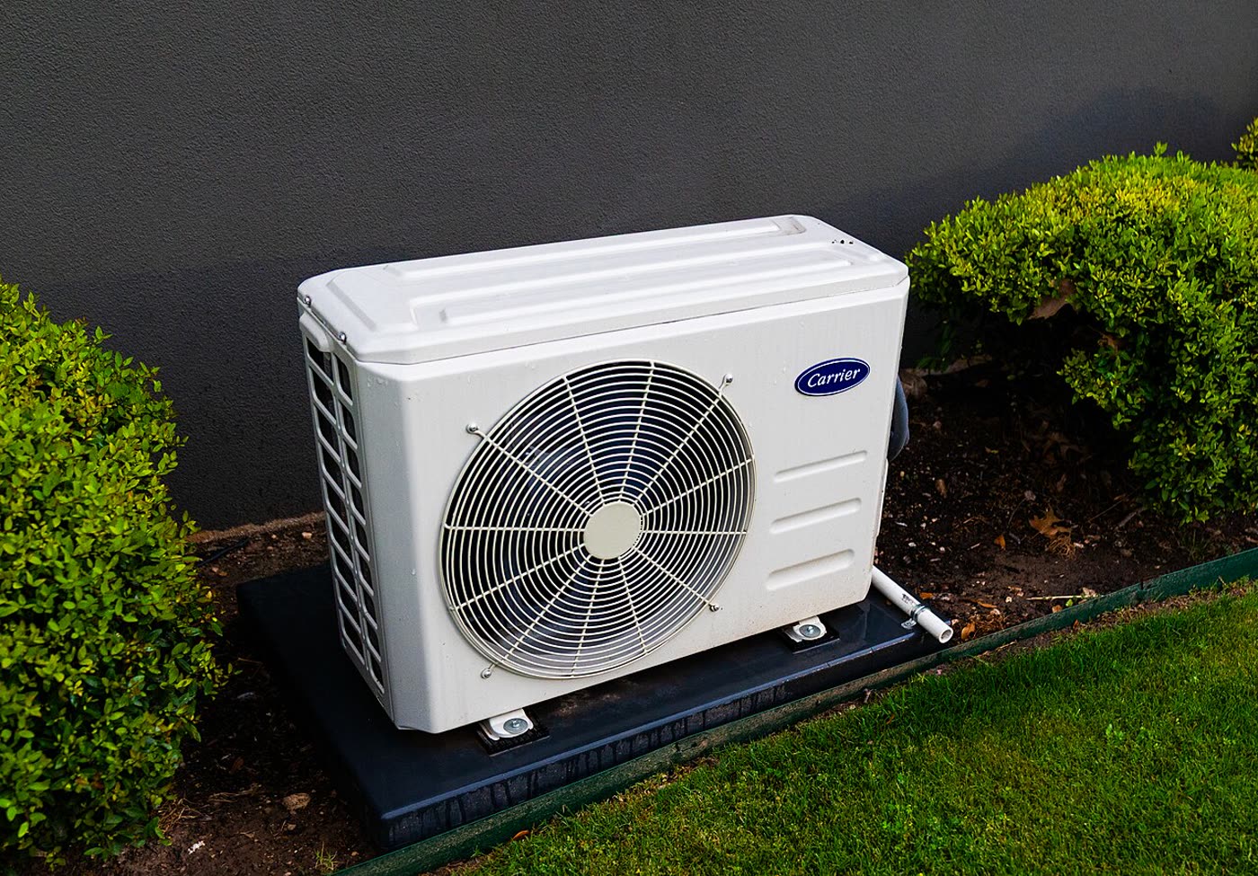 A Carrier outdoor unit on a pad, with the line cover leaving the cabinet