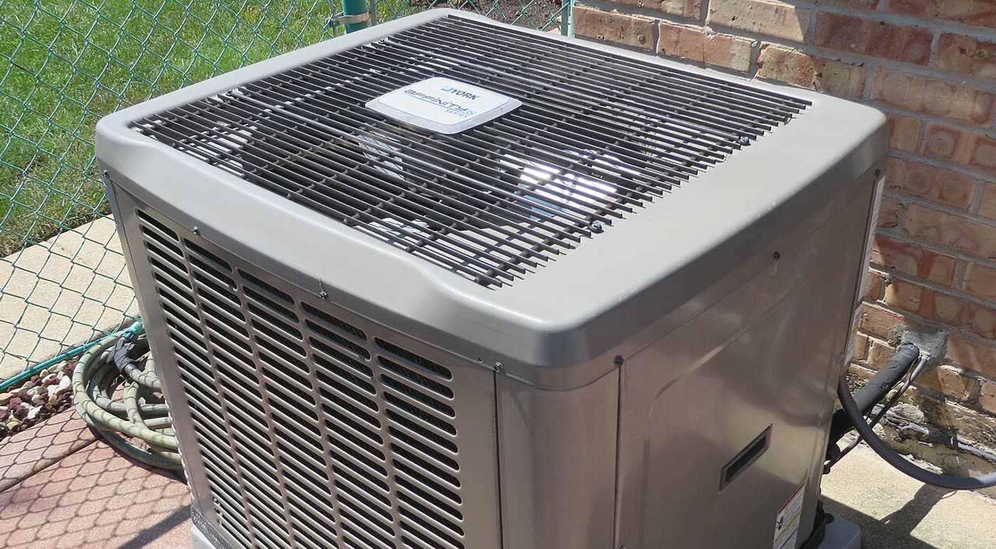 A York outdoor condenser on a concrete pad beside a brick wall
