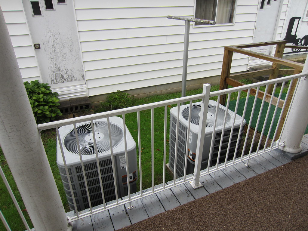 Two outdoor air conditioner condensers beside a house