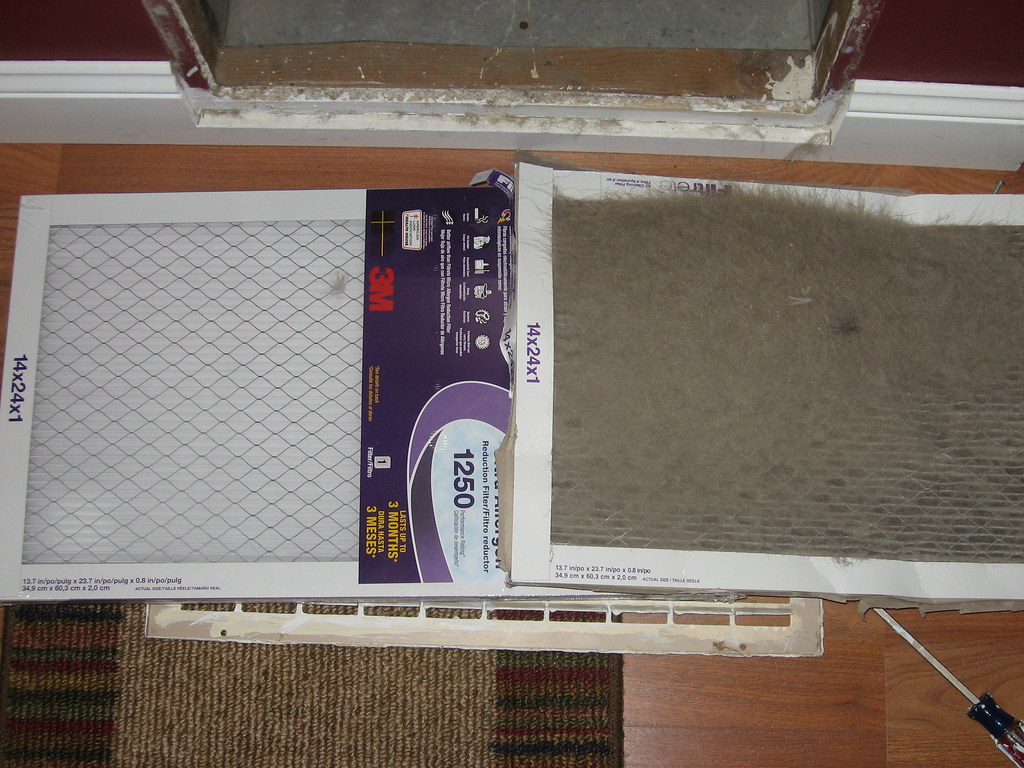 A new pleated air filter next to a filter packed with dust