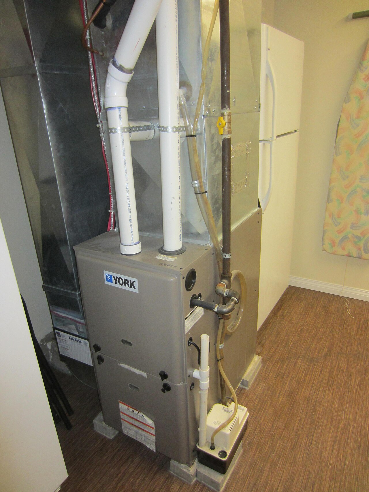 A York gas furnace in a utility room, with the flue and condensate line on top