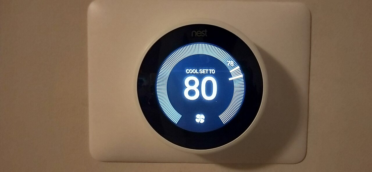 A Nest thermostat on a wall, set to cool at 80